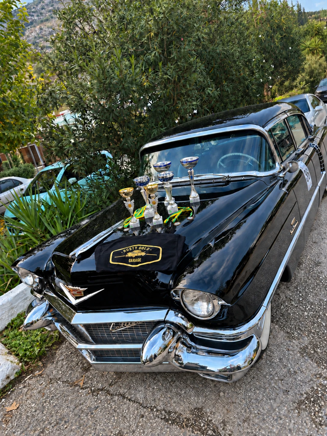 Rusty Gold Garage shirt and trophies on a classic Cadillac