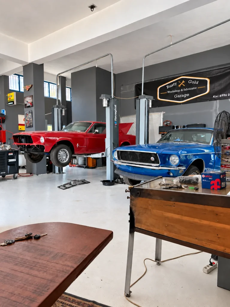 Red and blue classic Mustangs inside Rusty Gold Garage